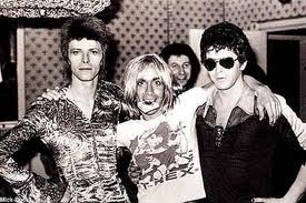 Four glammy, glittery icons party down in the early '70s (from left): David Bowie, Iggy Pop, and Lou Reed. The fourth? Why, Marc Bolan of course, as seen on Iggy's T. Rex T-shirt!